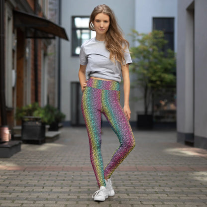 High waist Rainbow Leopard Glamour festival yoga leggings lifestyle view. The woman is standing in an outdoor setting wearing a grey t-shirt and white trainers.  The rainbow leopard glamour design is a bold animal printed pattern in black, grey and white against a blended rainbow background. Designed in Wales, UK | Sassy Seagull. 