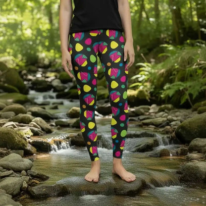 High waist Funk Party Original festival yoga leggings front view. The woman is standing in a rustic boho setting with plants, fairy lights and bunting in the background.  The Funk Party design is a bold colourful abstract print. Designed in Wales, UK | Sassy Seagull. 