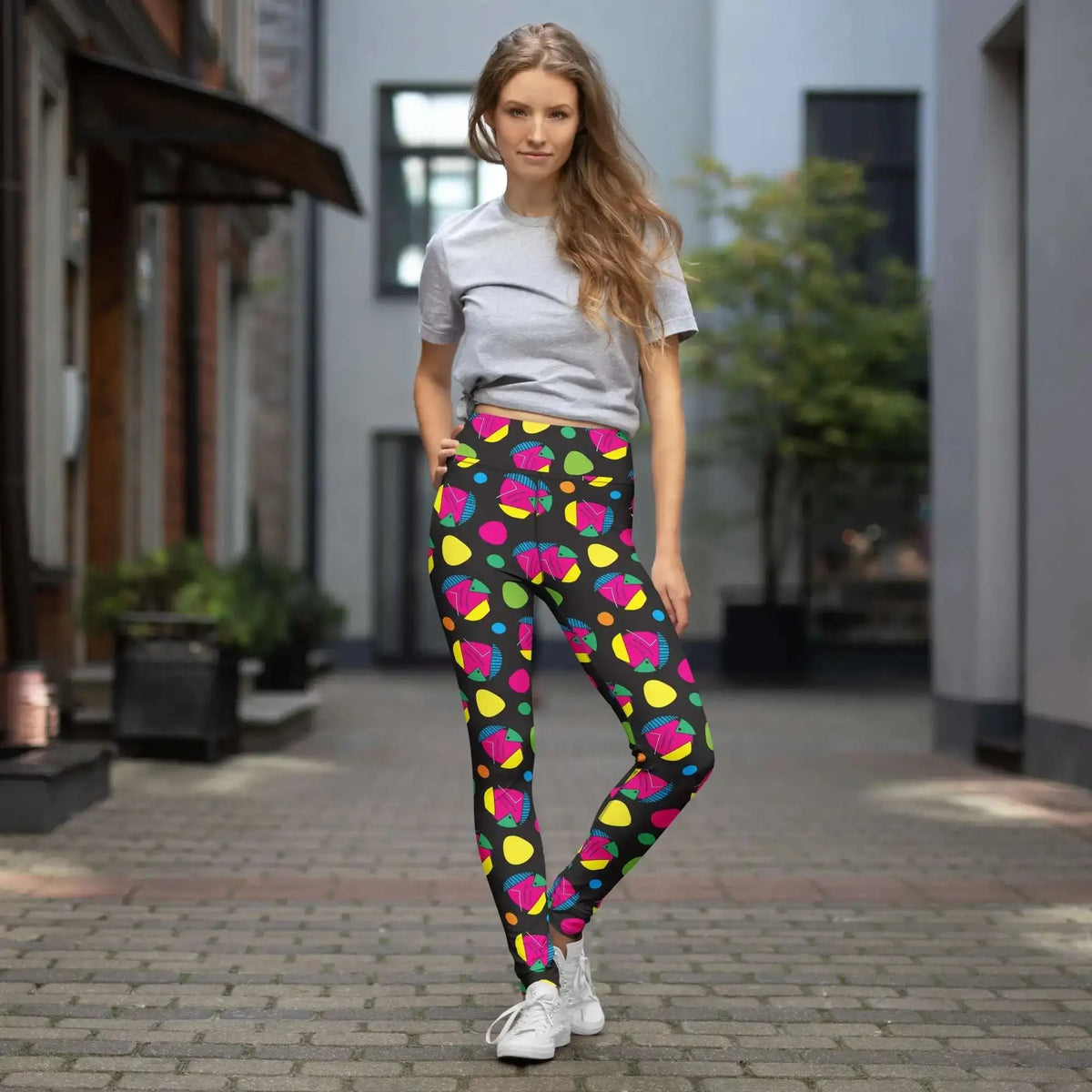 High waist Funk Party Original festival yoga leggings lifestyle view. The woman is standing in a an outdoor old-town setting.  The Funk Party design is a bold colourful abstract print. Designed in Wales, UK | Sassy Seagull. 