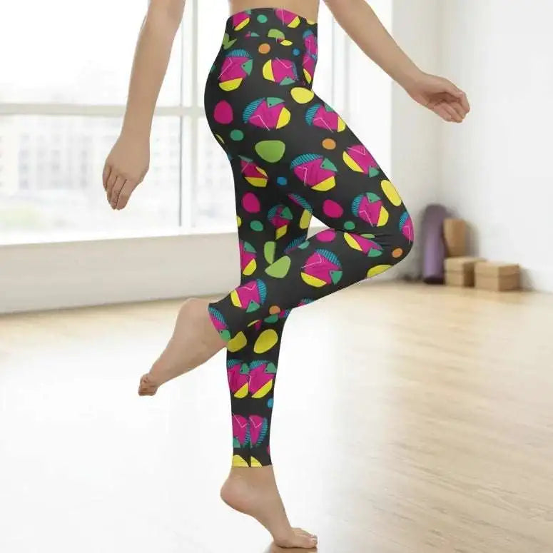 High waist Funk Party Original festival yoga leggings side view. The woman is standing in a rustic boho setting with plants, fairy lights and bunting in the background.  The Funk Party design is a bold colourful abstract print. Designed in Wales, UK | Sassy Seagull. 