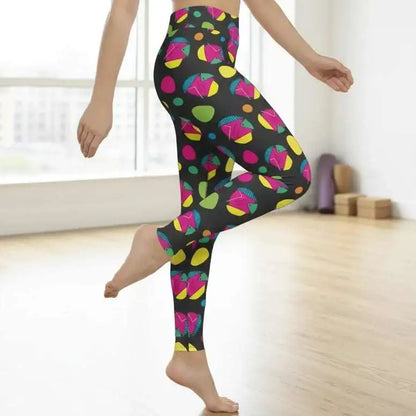 High waist Funk Party Original festival yoga leggings side view. The woman is standing in a rustic boho setting with plants, fairy lights and bunting in the background.  The Funk Party design is a bold colourful abstract print. Designed in Wales, UK | Sassy Seagull. 