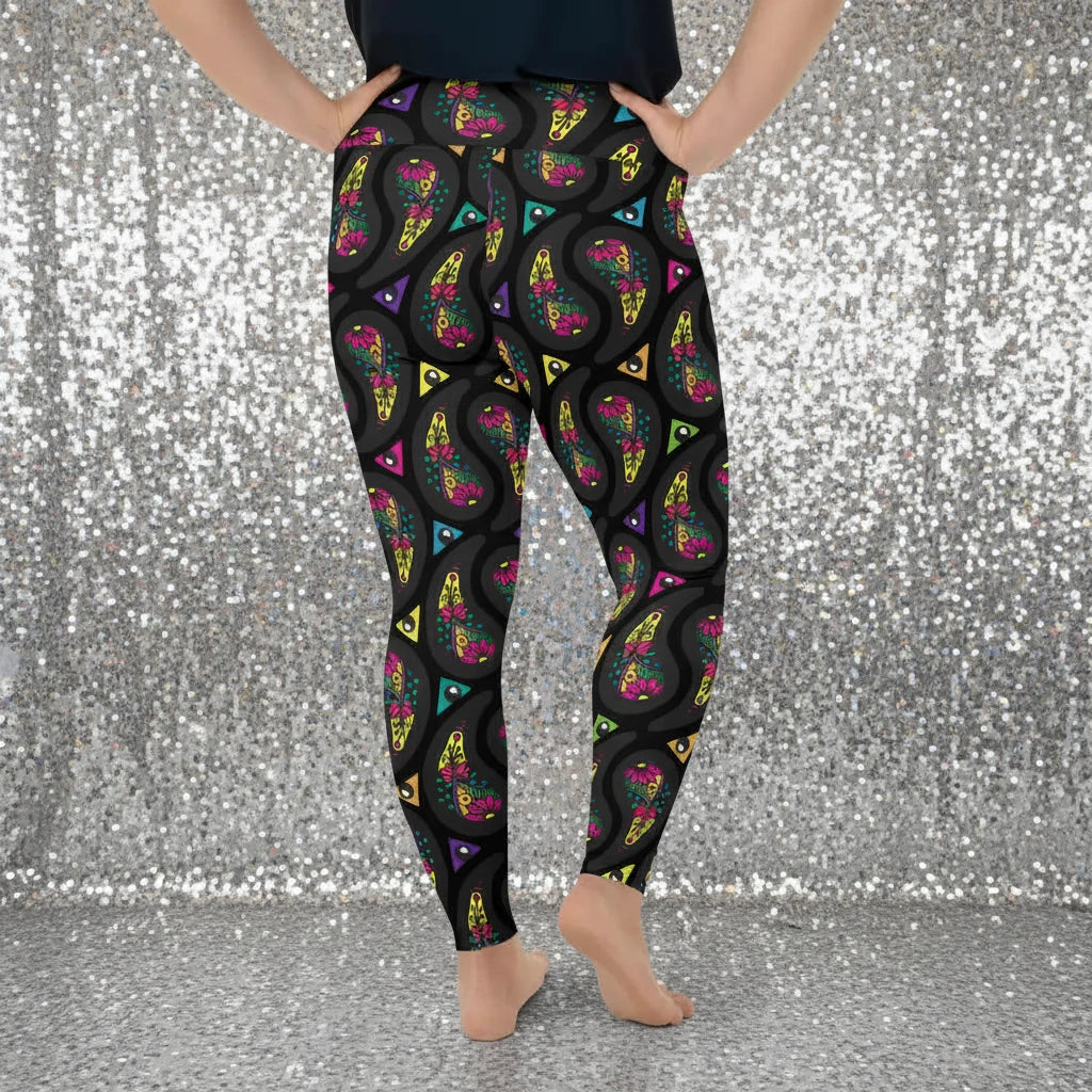 High waist Plus Size Black Paisley Party festival yoga leggings back view. Woman is standing in a boho interior room.  The Paisley Party design is a bold colourful rainbow geometric print pattern. Designed in Wales, UK | Sassy Seagull. 