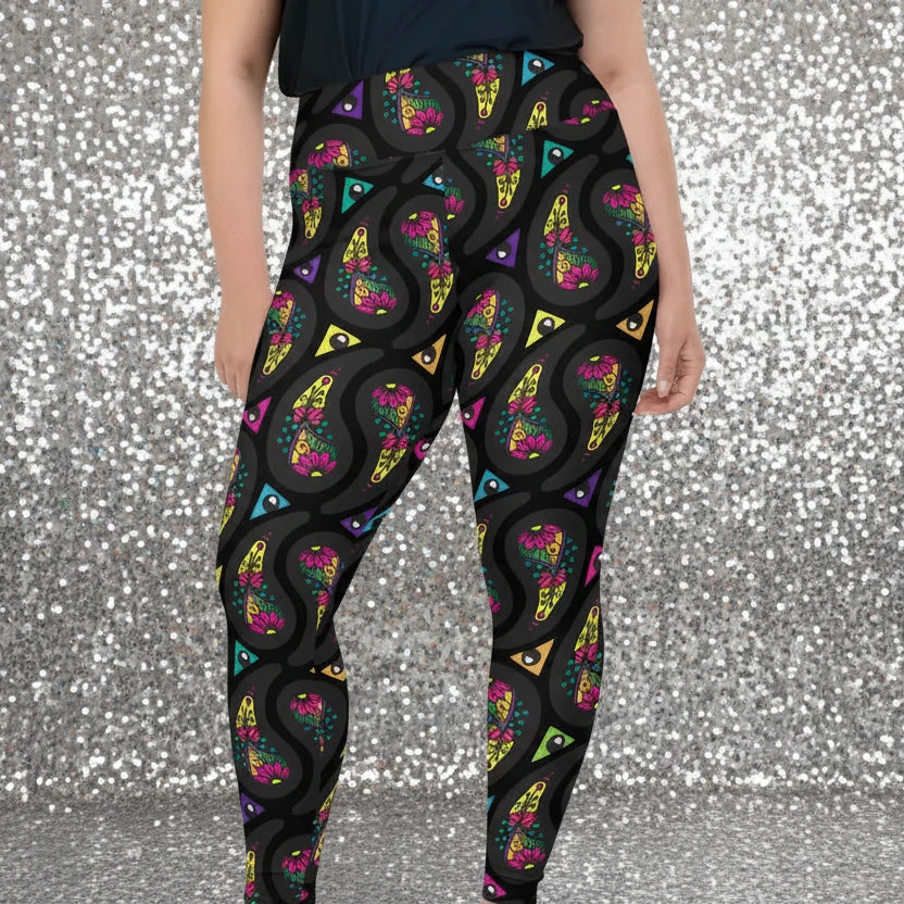 High waist Plus Size Black Paisley Party festival yoga leggings front view. Woman is standing in a boho interior room.  The Paisley Party design is a bold colourful rainbow geometric print pattern. Designed in Wales, UK | Sassy Seagull. 
