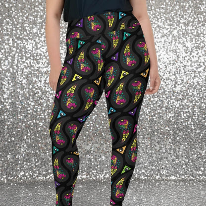 High waist Plus Size Black Paisley Party festival yoga leggings front view. Woman is standing in a boho interior room.  The Paisley Party design is a bold colourful rainbow geometric print pattern. Designed in Wales, UK | Sassy Seagull. 