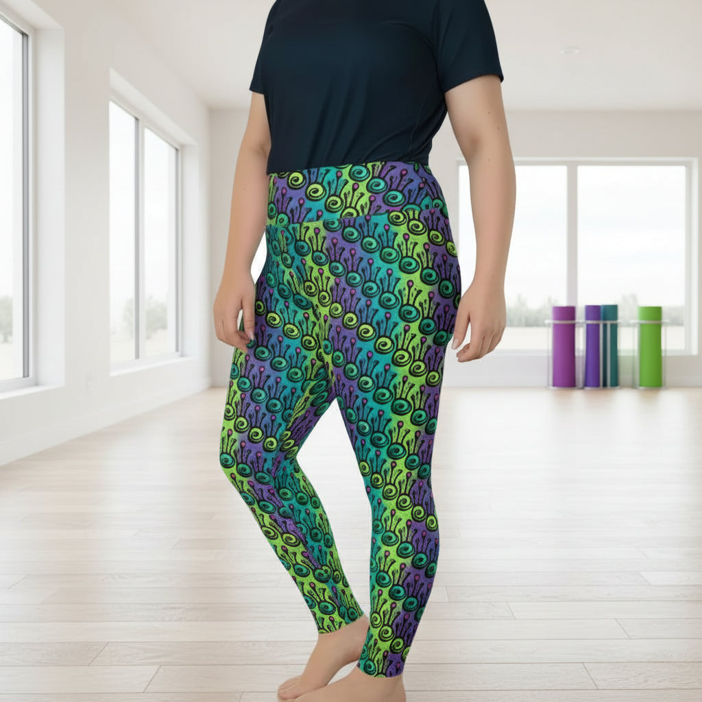 High waist Plus-Size Jungle Tribal Frog festival yoga leggings side view. Woman is standing in a boho interior room.  The Tribal Frog design is a bold colourful abstract print on a blended green, purple and blue background. Designed in Wales, UK | Sassy Seagull. 
