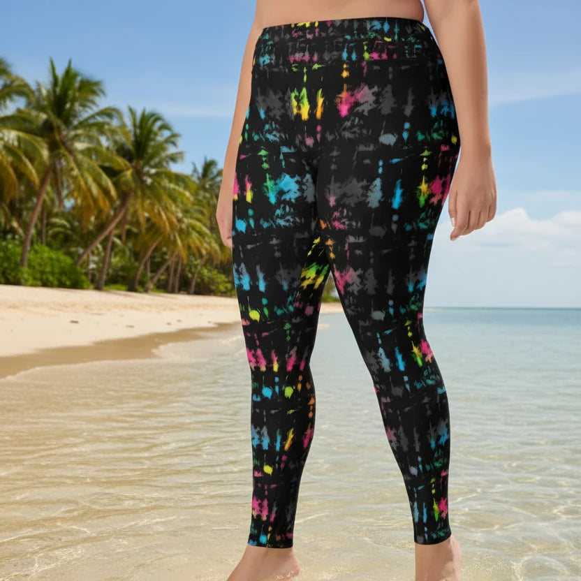 High waist Plus-Size Minstrel Magic festival yoga leggings side view. Woman is standing in a boho interior room.  The Minstrel Magic design is a bold colourful rainbow tie-dye inspired design. Designed in Wales, UK | Sassy Seagull. 