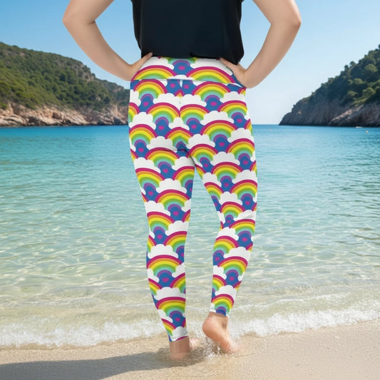 Plus-size high waist Rainbow Love festival yoga leggings back view. The woman is standing in a rustic boho setting with plants, fairy lights and bunting in the background.  The Rainbow Love design is a bold design featuring rainbows, white clouds and pink hearts. Designed in Wales, UK | Sassy Seagull. 