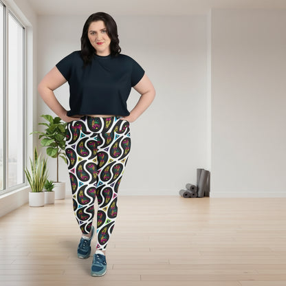 High waist Plus Size White Paisley Party festival yoga leggings lifestyle view. Woman is standing in a boho interior room.  The Paisley Party design is a bold colourful rainbow geometric print pattern. Designed in Wales, UK | Sassy Seagull. 