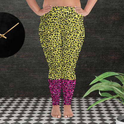 A curvy woman from the waist down wearing plus-size high-waist Yellow and Pink Leopard Glamour funky festival yoga leggings standing facing forwards. The woman is standing in front of a textured grey background with a black and gold wall clock to the left and a partially visible leafy plant on the floor in the bottom right.  This design features an animal print pattern in black, grey and white, printed at a medium scale. The top 3/4 background is bright yellow with the bottom 1/4 a hot pink colour