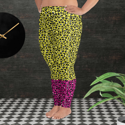 A curvy woman from the waist down wearing plus-size high-waist Yellow and Pink Leopard Glamour funky festival yoga leggings standing facing left. The woman is standing in front of a textured grey background with a black and gold wall clock to the left and a partially visible leafy plant on the floor in the bottom right.  This design features an animal print pattern in black, grey and white, printed at a medium scale. The top 3/4 background is bright yellow with the bottom 1/4 a hot pink colour