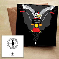 Black Greeting Card with a punk rock seagull with wings spread, riding a motorbike with a cloud of smoke behind it.  The card is on a brown envelope on a wooden table.