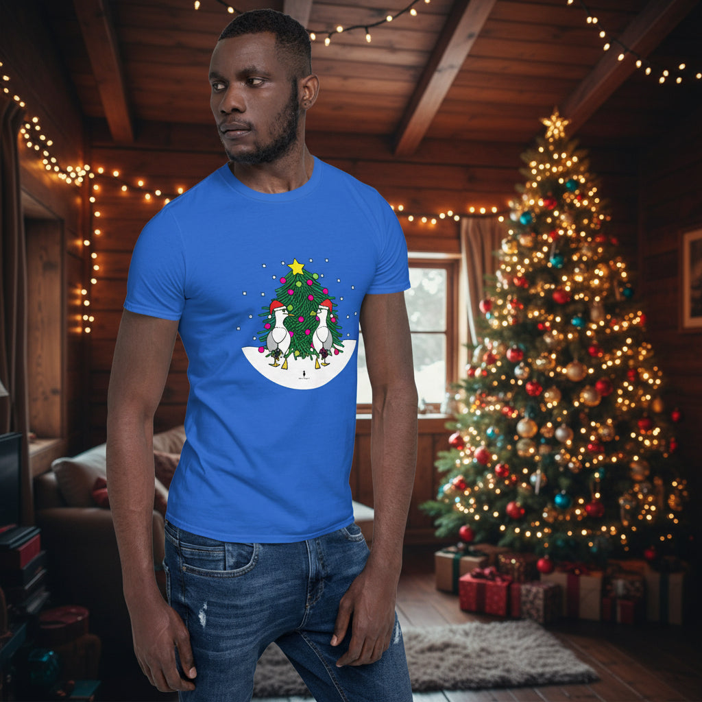 Person wearing a royal blue 100% cotton Christmas t-shirt with two sassy seagulls in front of a decorated Christmas tree. The person is standing in a wooden chalet decorated for Christmas.