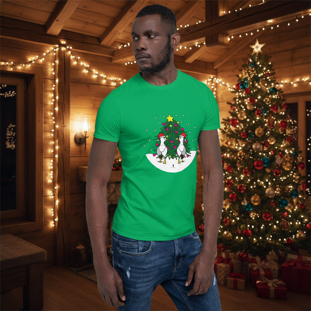 Person wearing a green 100% cotton Christmas t-shirt with two sassy seagulls in front of a decorated Christmas tree. The person is standing in a wooden chalet decorated for Christmas.