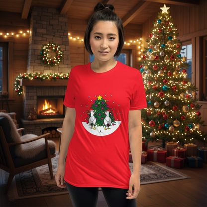 Person wearing a red 100% cotton Christmas t-shirt with two sassy seagulls in front of a decorated Christmas tree. The person is standing in a wooden chalet decorated for Christmas.