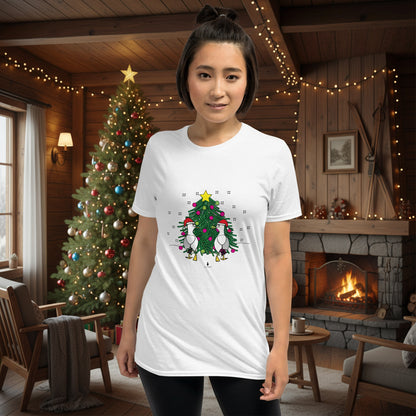 Person wearing a white 100% cotton Christmas t-shirt with two sassy seagulls in front of a decorated Christmas tree. The person is standing in a wooden chalet decorated for Christmas.