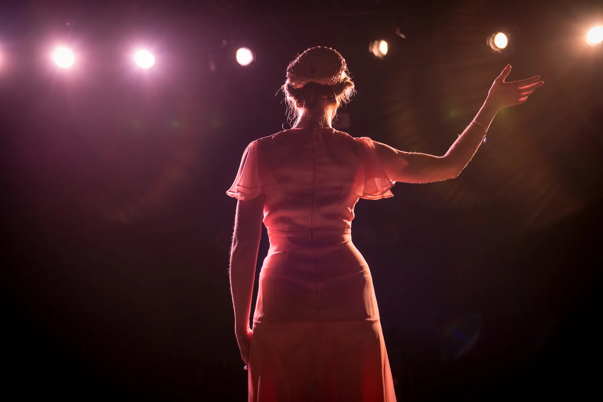Woman-in-a-red-dress-standing-on-a-dark-stage-with-spotlights.
