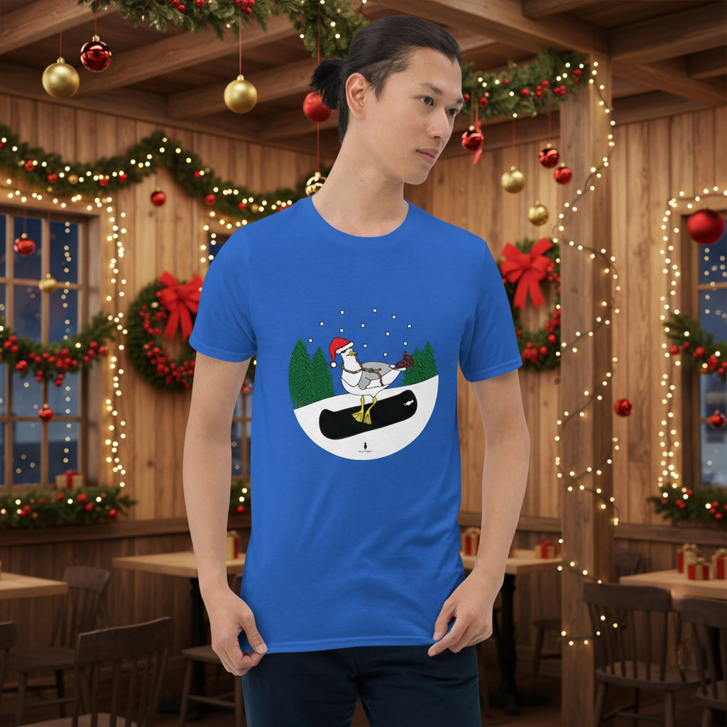 Man wearing a royal blue 100% cotton snowboarding seagull Christmas t-shirt, in a rustic cafe filled with red, green and gold Christmas decorations