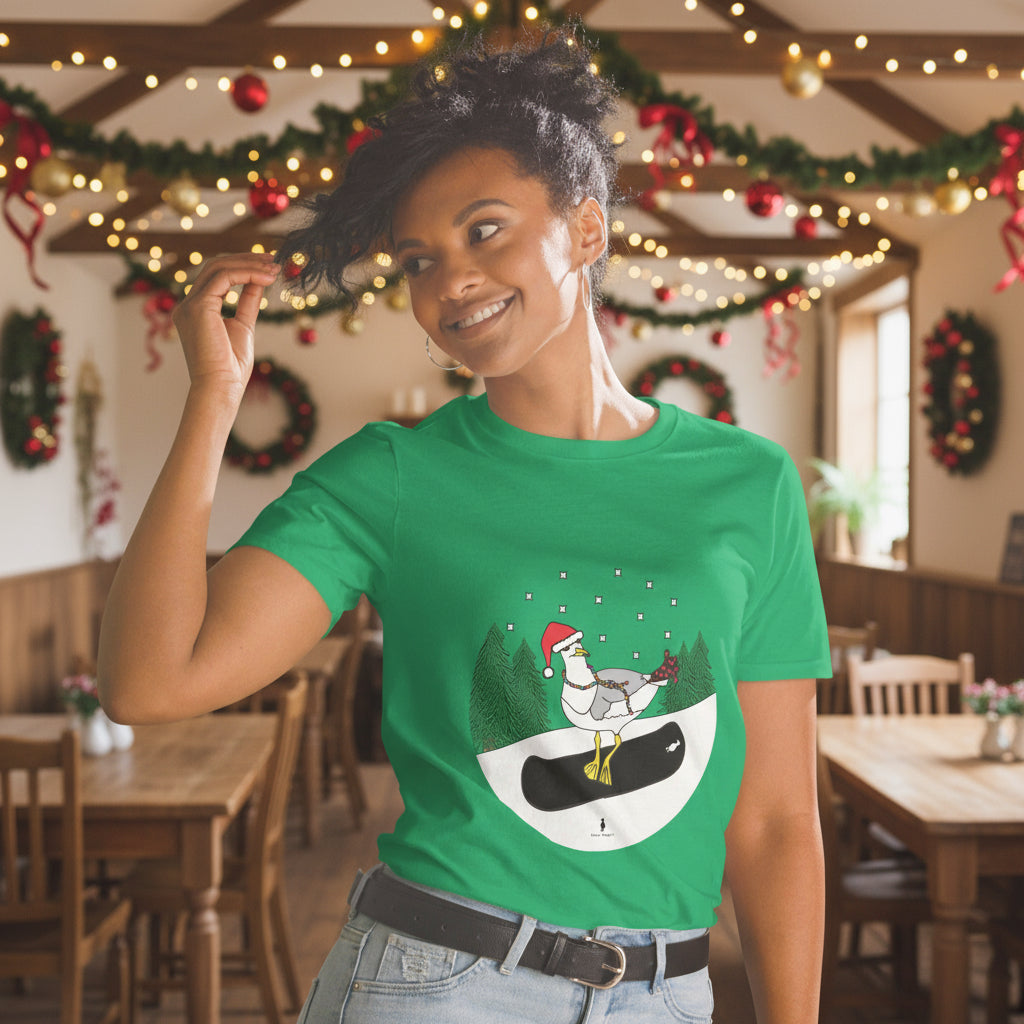 Woman wearing an Irish green 100% cotton snowboarding seagull Christmas t-shirt, in a rustic cafe filled with red, green and gold Christmas decorations
