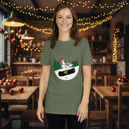 Woman wearing a khaki green 100% cotton snowboarding seagull Christmas t-shirt, in a rustic cafe filled with red, green and gold Christmas decorations