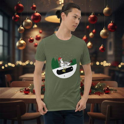 Man wearing a khaki green 100% cotton snowboarding seagull Christmas t-shirt, in a rustic cafe filled with red, green and gold Christmas decorations